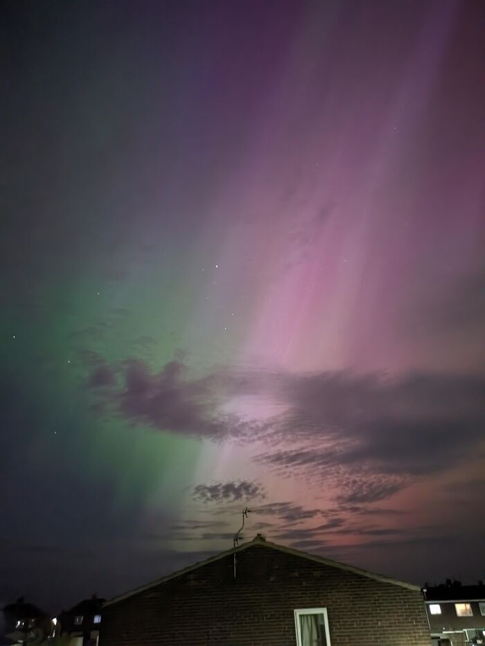 Northern lights display with purple and green hues over rooftops
