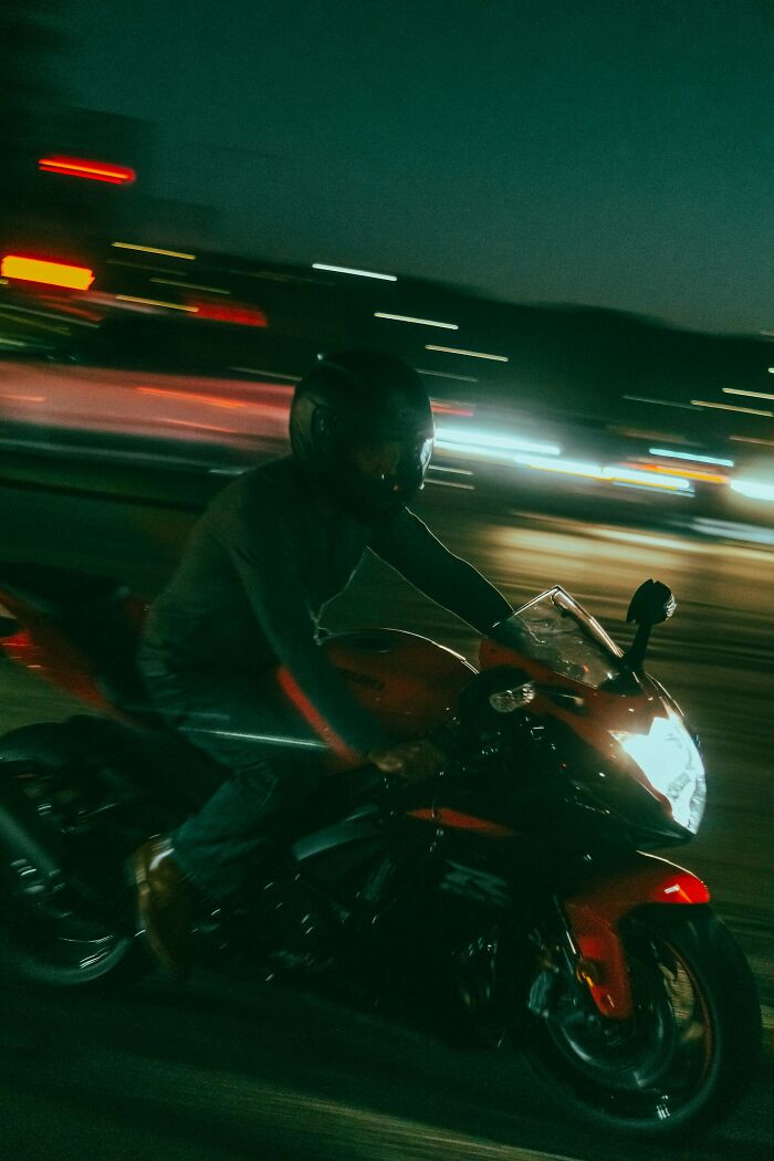 Person riding a motorcycle at night with blurred city lights in background terrifying experience