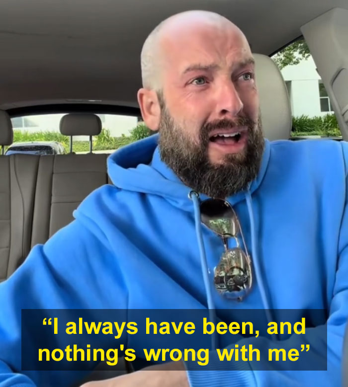 A man in a blue hoodie with a beard, looking emotional, finding nothing's wrong with him after a diagnosis.