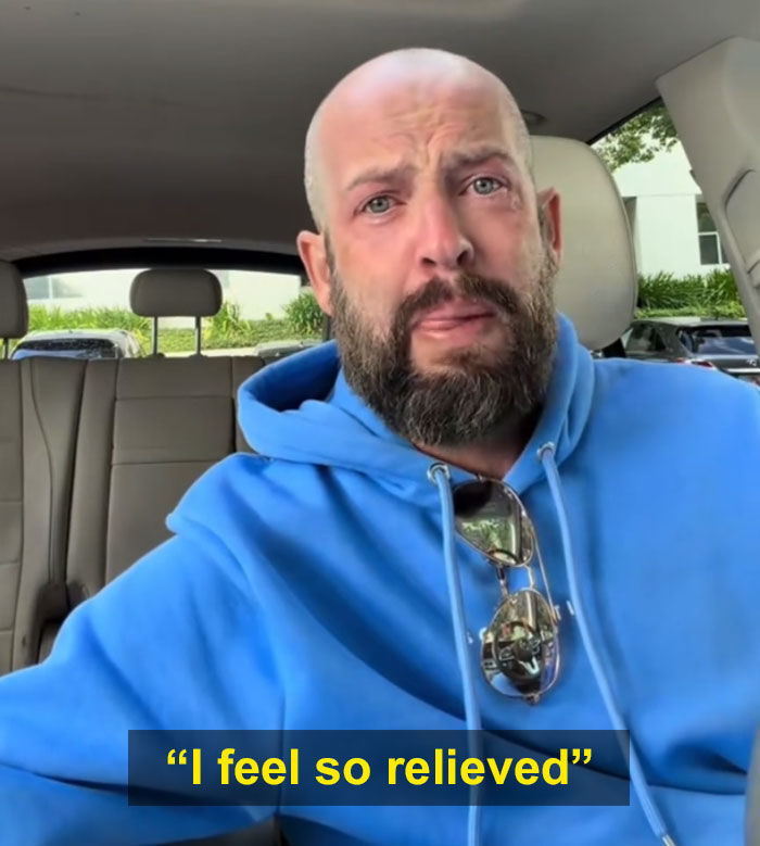 Man with beard and blue hoodie, tears in his eyes, feeling relieved after a diagnosis, no longer thinking something is wrong with him.
