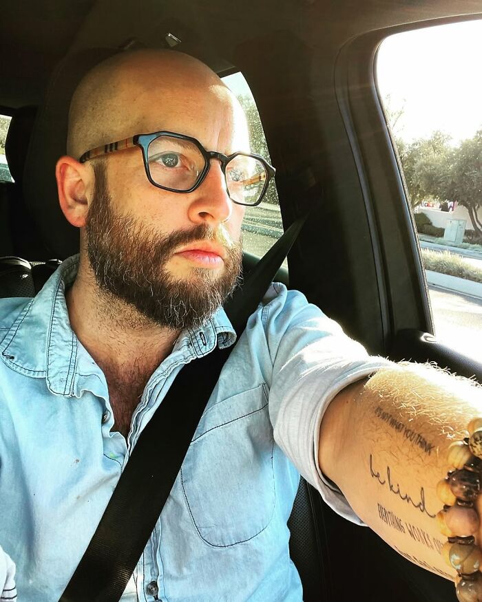Man with a beard and glasses in a light blue shirt, wearing a seatbelt, looking thoughtful in a car. Life-changing diagnosis.