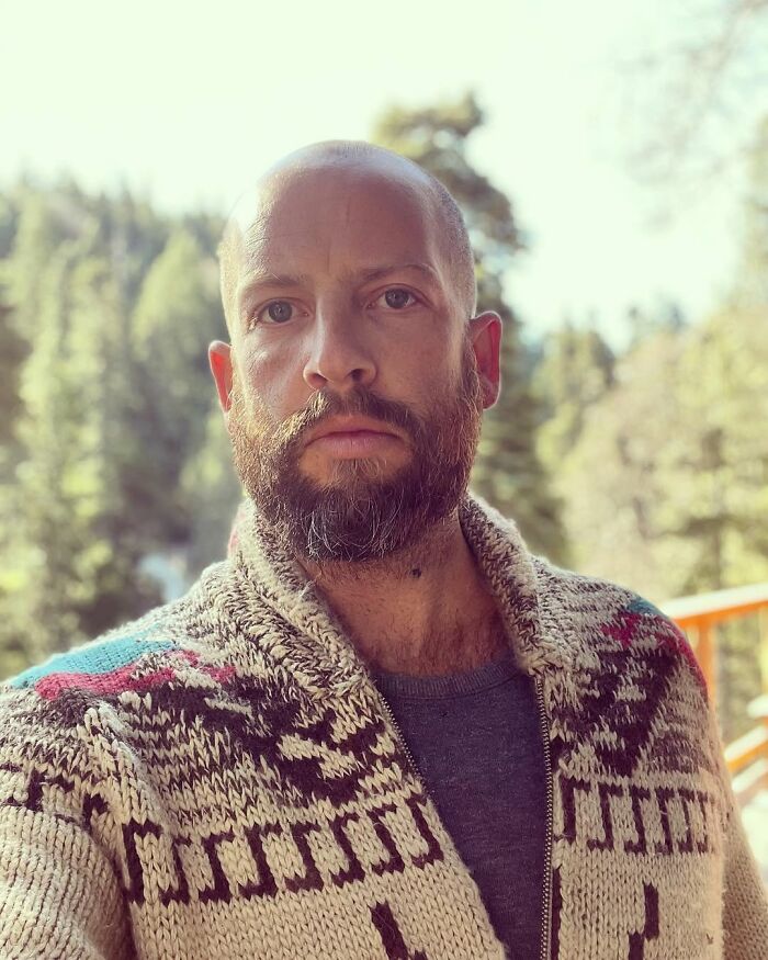 A bearded man, looking intently at the camera, wearing a patterned cardigan. His life changes after one diagnosis.
