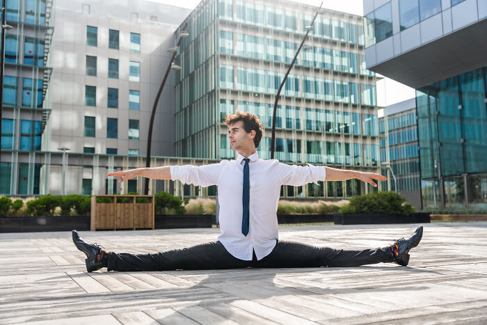 Man doing splits outside modern buildings, showing fitness and flexibility of long term partners