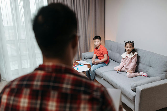 Man talking with children and parent in a home setting about family matters