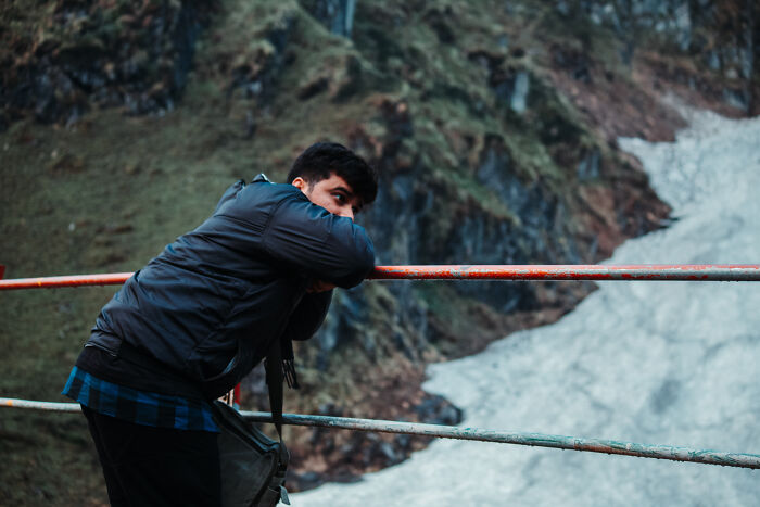 Man leaning on railing near snowy mountain, reflecting contemplation in long term partners