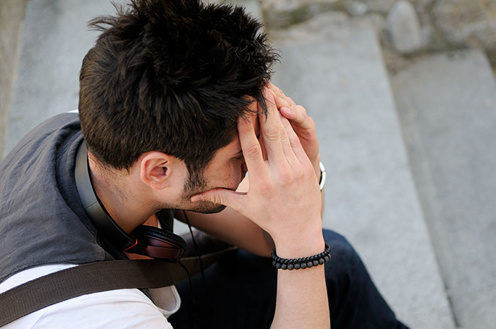 Man with hands on his head, looking downcast, sitting on steps. He feels heartbroken after an affair. Man with hands on his head, looking downcast, sitting on steps. He feels heartbroken after an affair.