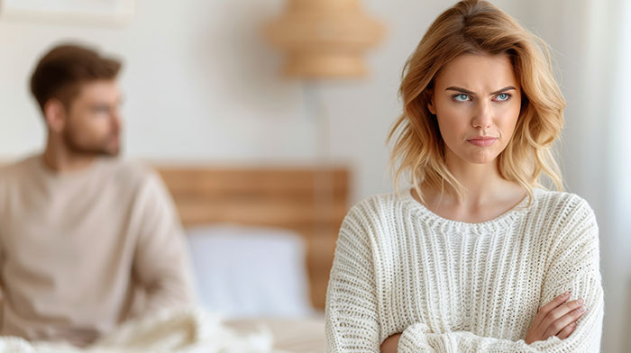 A woman with an angry expression, arms crossed, with a blurred man in the background. Her ex wants to reconcile after her affair. A woman with an angry expression, arms crossed, with a blurred man in the background. Her ex wants to reconcile after her affair.