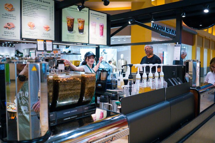 Busy coffee shop counter with barista making drinks and coffee machines