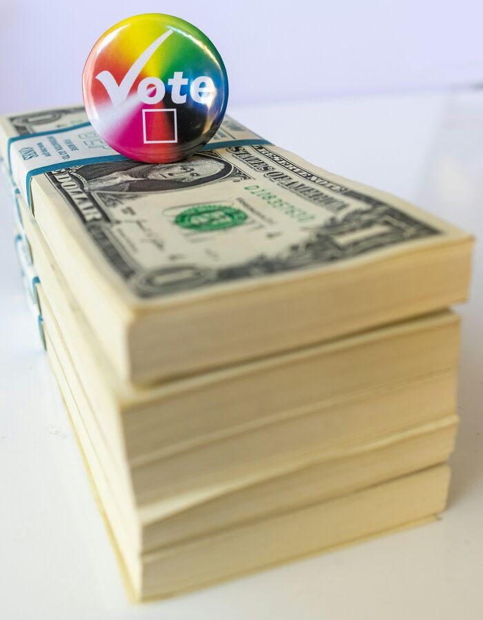 Stack of US dollar bills with vote button highlighting money and voting