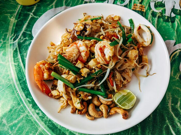 Plate of shrimp pad thai with cashews and lime showcasing geography facts