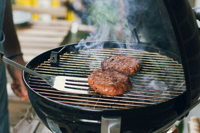 Close-up of burgers grilling on barbecue with smoke rising