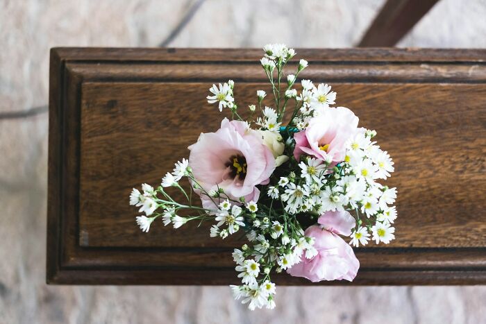 A small bouquet of pink and white flowers on a wooden surface, ready for hilarious engagement stories.
