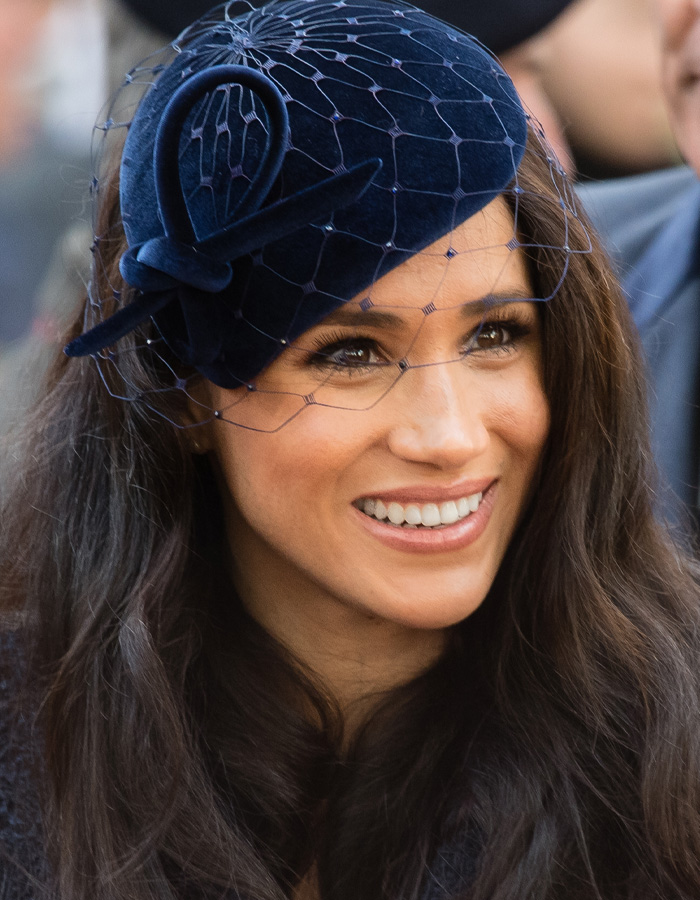 Smiling Meghan Markle wearing a blue hat with veil showing changing appearance