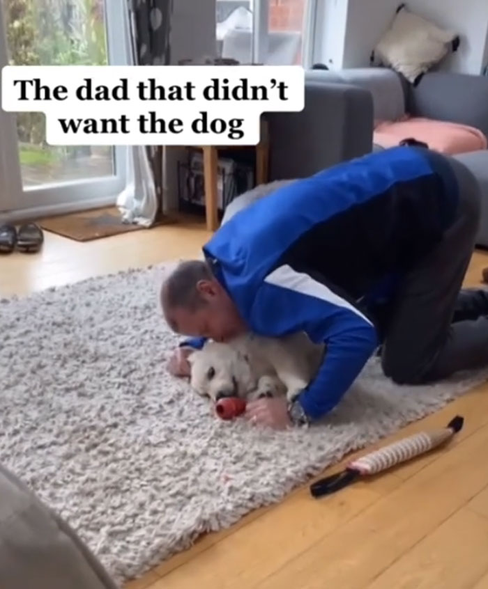 A man affectionately snuggling with a cute white puppy on a rug, highlighting men getting a pet against their will.