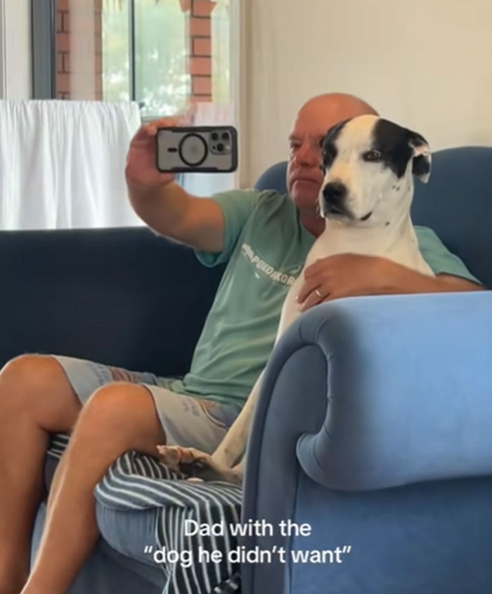 A man in a green shirt takes a selfie with a black and white pet dog, showcasing men getting pets.