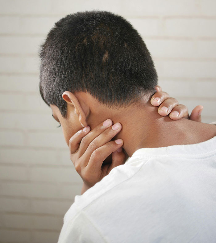 A person touching their neck as if in pain, suggesting stress from messed up school stories.