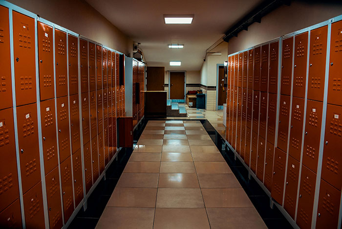 A dimly lit school hallway lined with orange lockers, evoking messed up school stories and younger years.