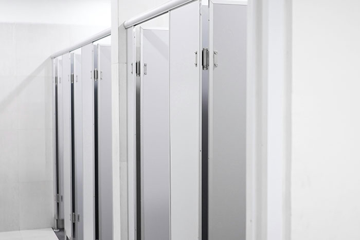 White stalls in a school bathroom, depicting a common setting for many messed up school stories.