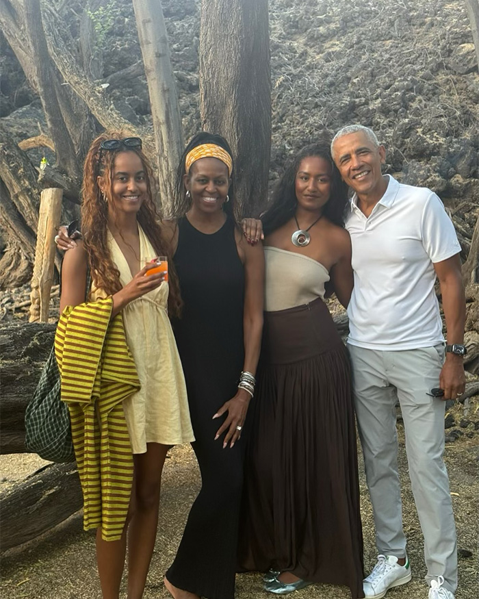 Michelle Obama with family outdoors smiling and posing by trees