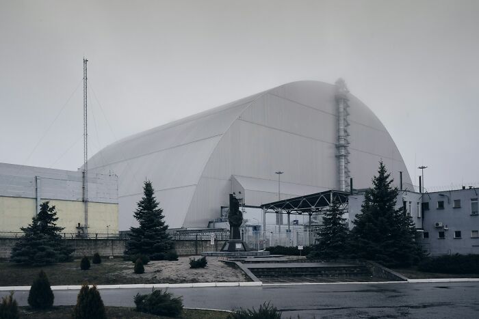 Chernobyl New Safe Confinement, a massive arch structure, on a foggy day. An epic comeback in nuclear safety.