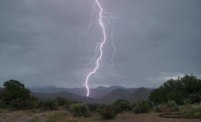 Lightning striking over mountain landscape during storm