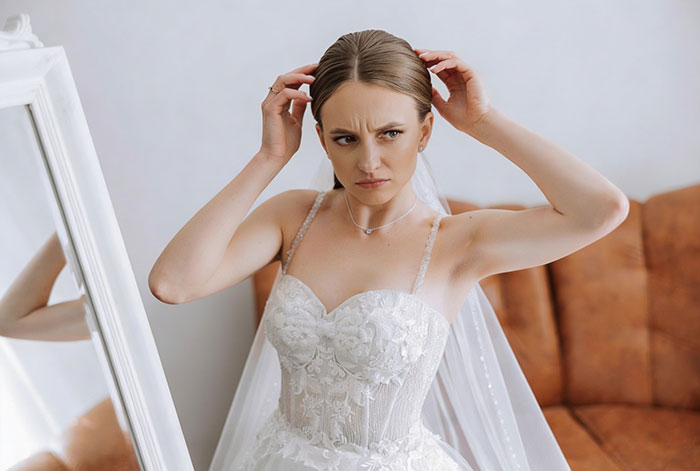 Bride looking upset in white wedding dress adjusting hair Bride looking upset in white wedding dress adjusting hair