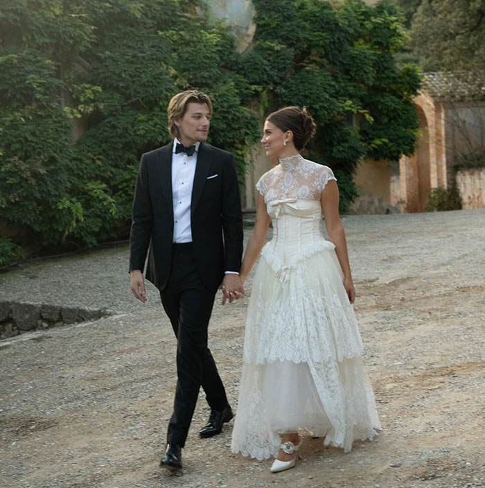 Millie Bobby Brown and Jake Bongiovi holding hands in wedding attire Millie Bobby Brown and Jake Bongiovi holding hands in wedding attire