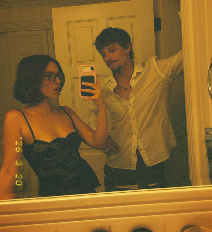 Millie Bobby Brown and Jake Bongiovi taking a mirror selfie in dim lighting Millie Bobby Brown and Jake Bongiovi taking a mirror selfie in dim lighting