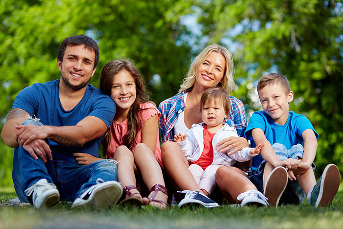 Happy family sitting outdoors with children on grass in a park setting