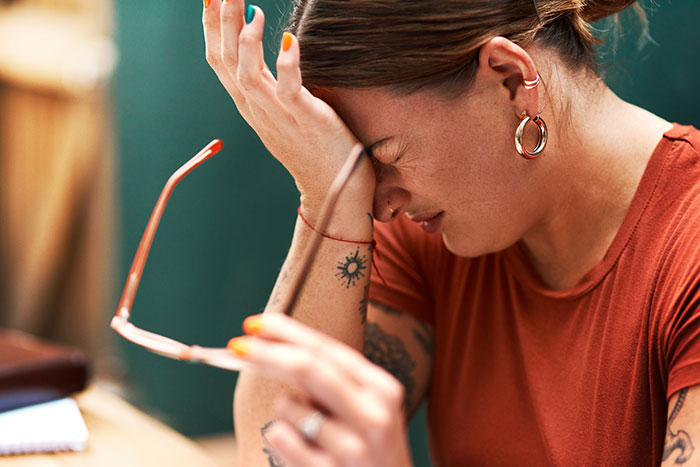 Woman holding head in frustration over pressures of traditional SAHM values