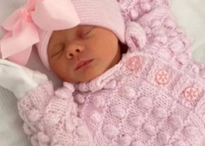 Sleeping newborn baby dressed in pink at gender reveal party