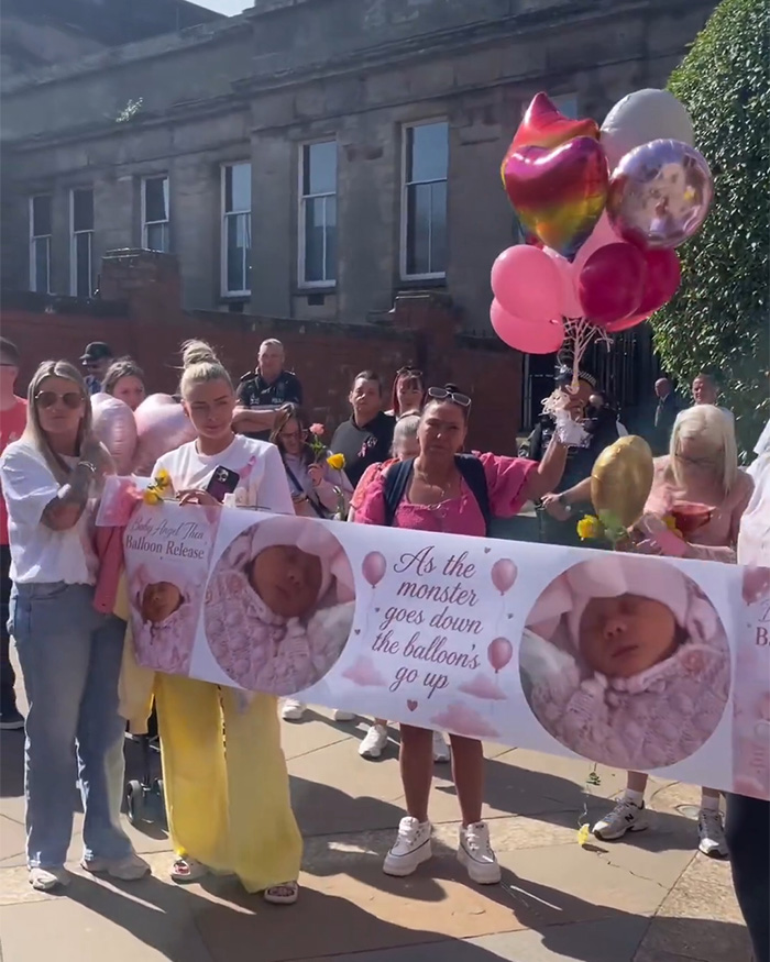 Group holding banner and balloons at memorial balloon release