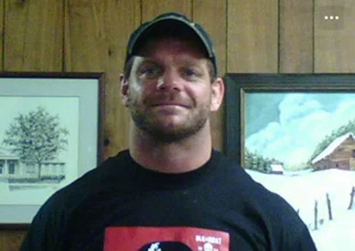 Smiling man wearing a black cap and black t-shirt standing indoors