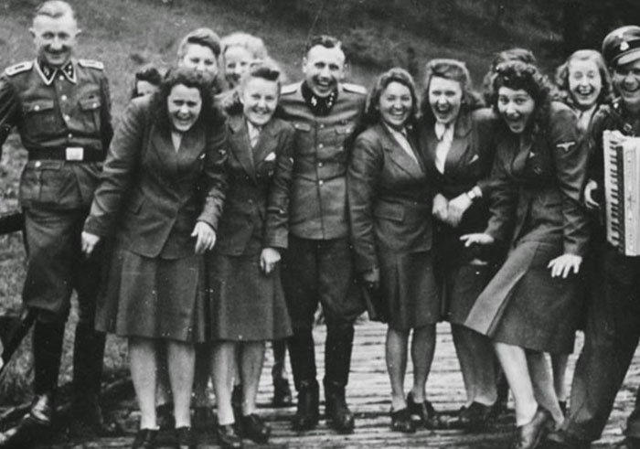 Group of World War II era military personnel and women posing and laughing together