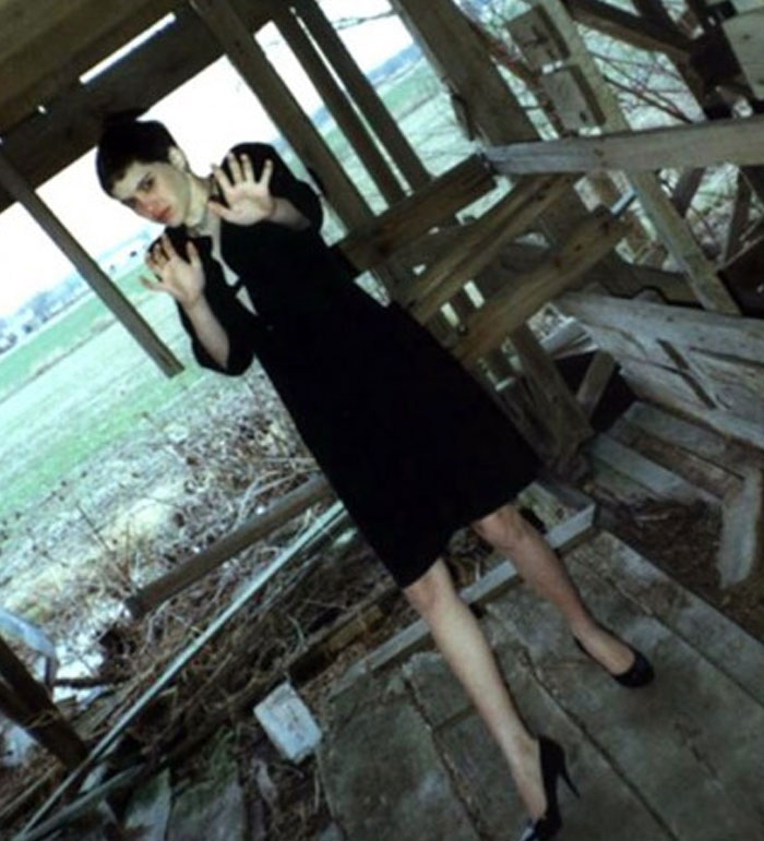 Disturbing elongated-legged woman posing in wooden shed