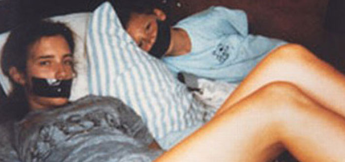 Two girls with gagged mouths lying on a couch