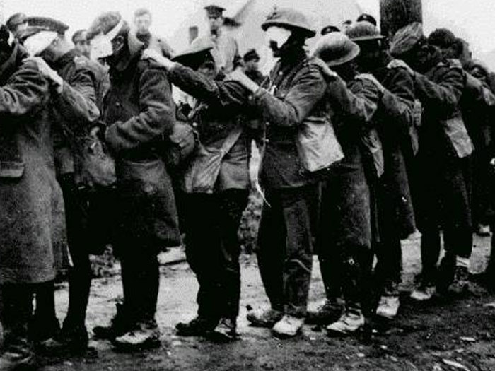 Black and white photo of blindfolded men standing in a line during historic wartime