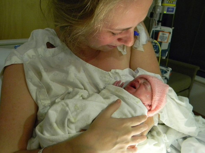 Mother holding and smiling at her newborn baby in hospital