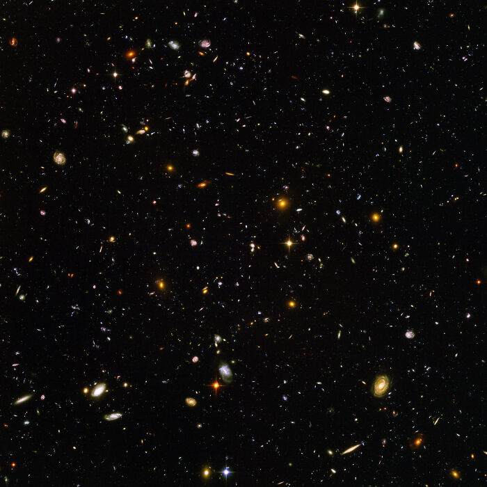 Powerful photo showing a vast field of distant galaxies in deep space with stars and cosmic light