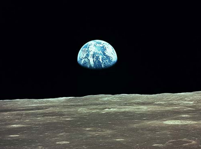 Earth rising over the moon surface in a powerful space photograph