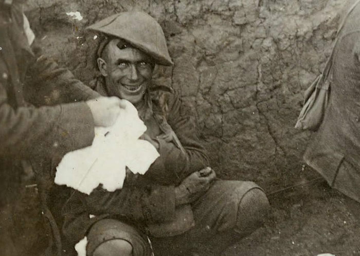 Powerful photo of a smiling World War I soldier in a trench receiving medical care