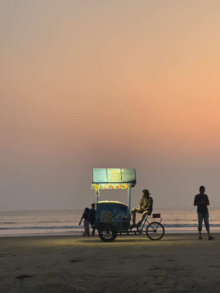 Evening beach scene with illuminated ice cream cart and people in random camera clicks