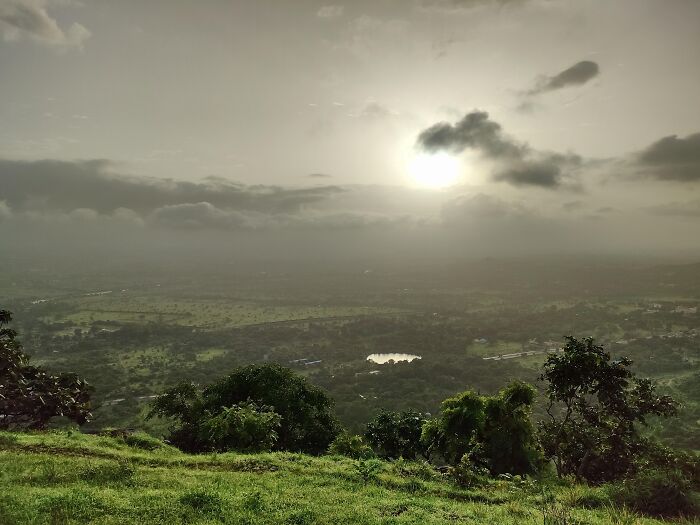 Panoramic view of a green landscape under a cloudy sky with sun shining