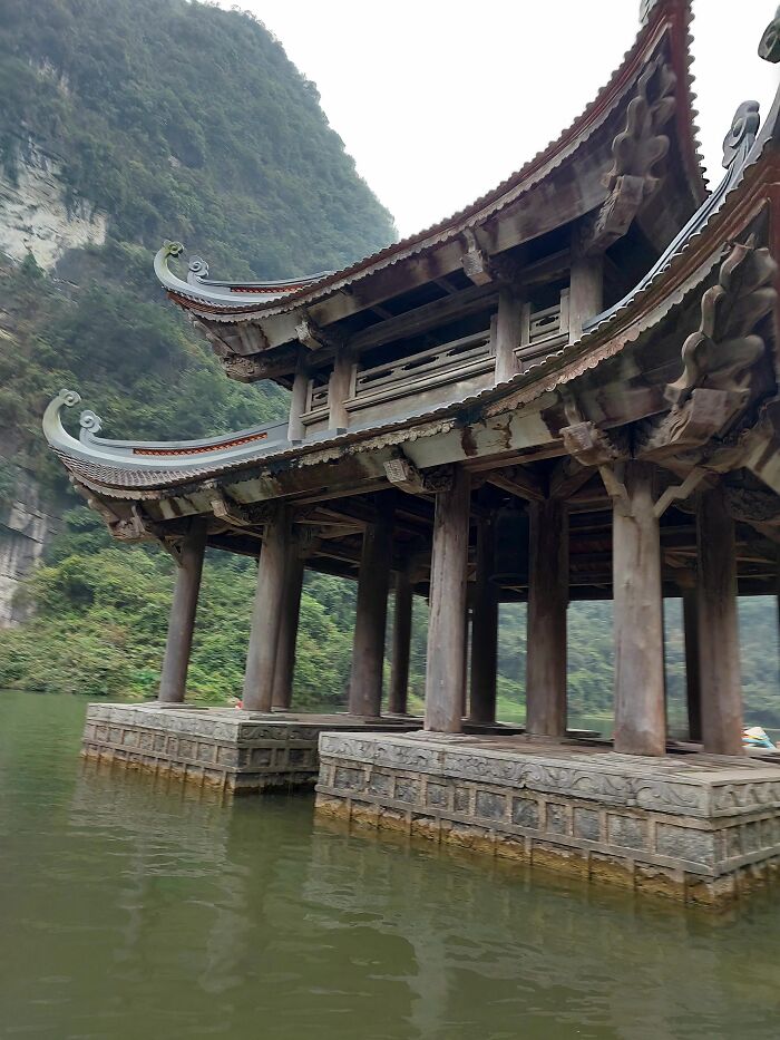Ancient temple with curved roof pillars over water surrounded by green mountains random camera clicks