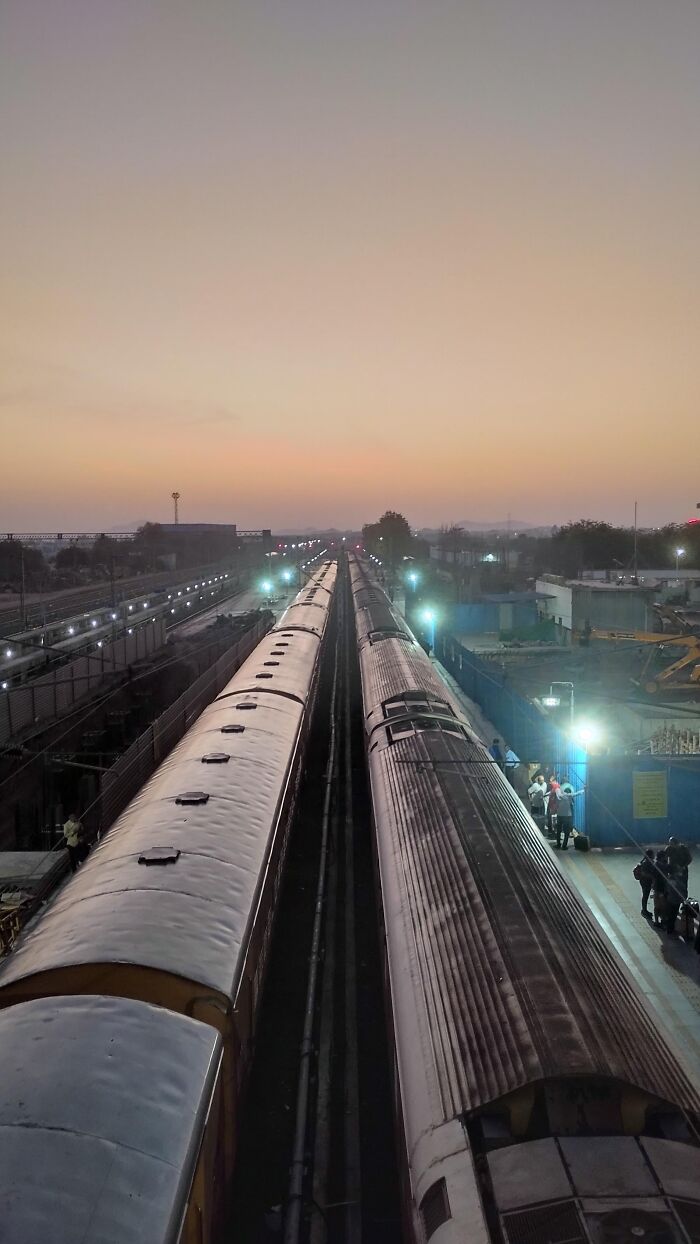 Two trains on parallel tracks at station during dusk in incredible photo