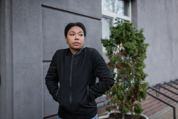 A young Black woman in a black jacket looks concerned, highlighting the importance of routine cancer screening.