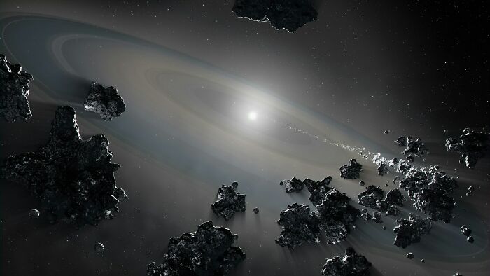 A bright star in a dark galaxy, surrounded by a ring and numerous asteroids, illustrating a scientific fact about space.