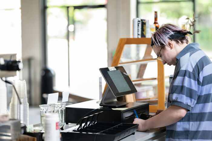 Cashier closing register drawer in a small store symbolizing choosing peace over paycheck