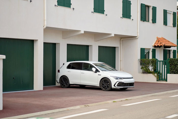 White car parked outside house with green doors and nightmare neighbor context