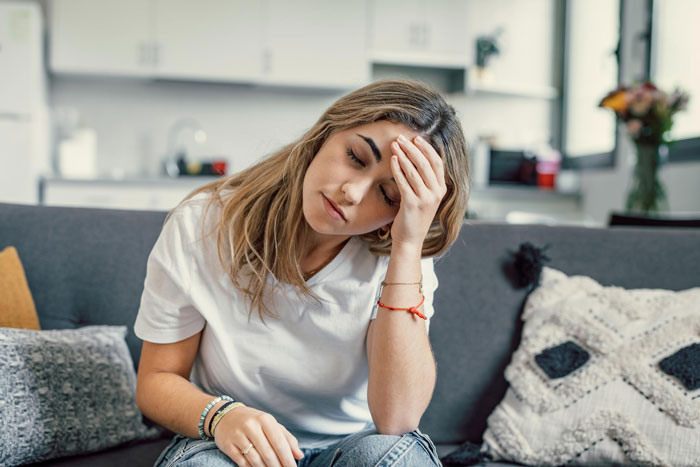 A woman on a couch looking pensive, reflecting on a funny neighbor running misunderstanding. A woman on a couch looking pensive, reflecting on a funny neighbor running misunderstanding.